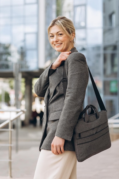 Ritratto di una donna d'affari matura sorridente con emozioni su un ufficio moderno e sullo sfondo urbano