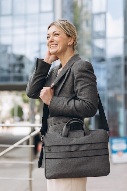 Foto ritratto di una donna d'affari matura sorridente con emozioni su un ufficio moderno e sullo sfondo urbano