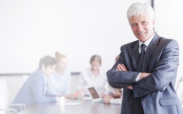 Portrait of mature businessman in front of his team in office