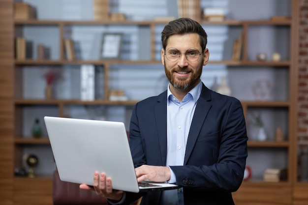 Portrait of mature businessman inside office senior man in business suit and beard standing and