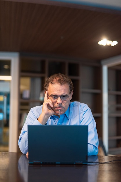 Портрет зрелого бизнесмена, использующего портативный компьютер в офисе, горизонтальный снимок