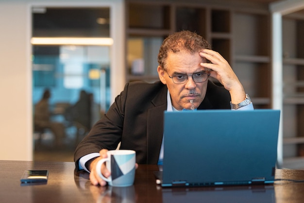 Portrait of mature businessman using laptop computer in office horizontal shot