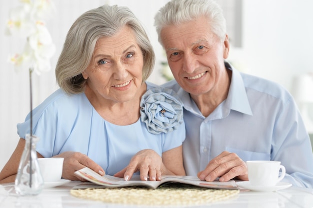 Portrait of mature couple with magazine drinking tea at home