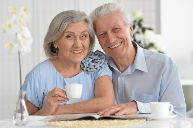 Photo portrait of mature couple with magazine drinking tea