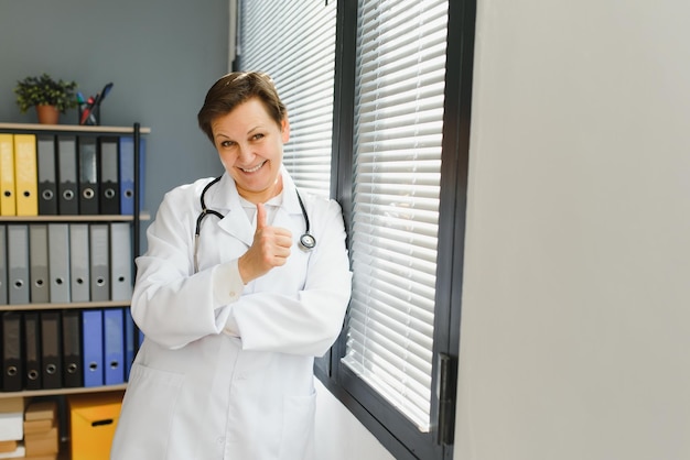 Portrait of mature female doctor in white coat at workplace