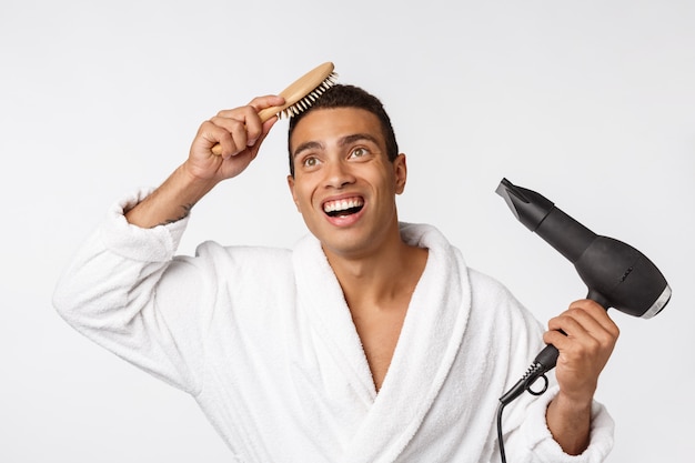 Portrait of mature funny beautiful tan-skinned guy with curly hair in casual white bathrobe