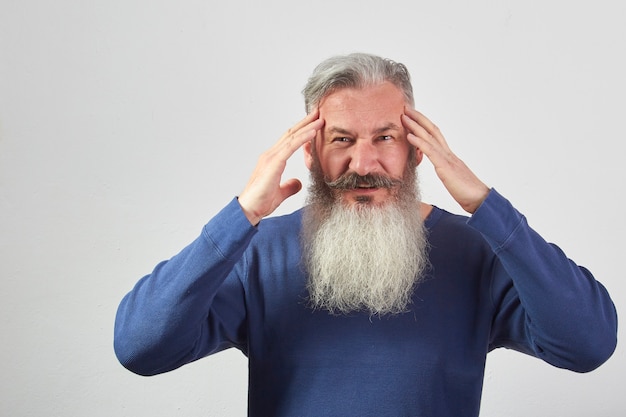 Portrait of mature gray-haired bearded man in blue sweatshirt with a headache