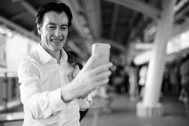 Portrait of mature handsome businessman exploring around the city in black and white