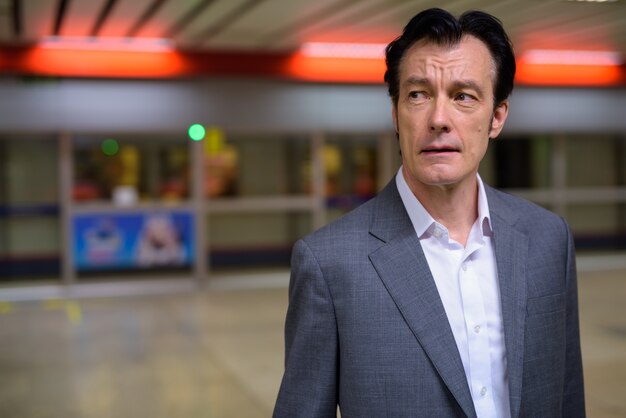 Portrait of mature handsome businessman in train station