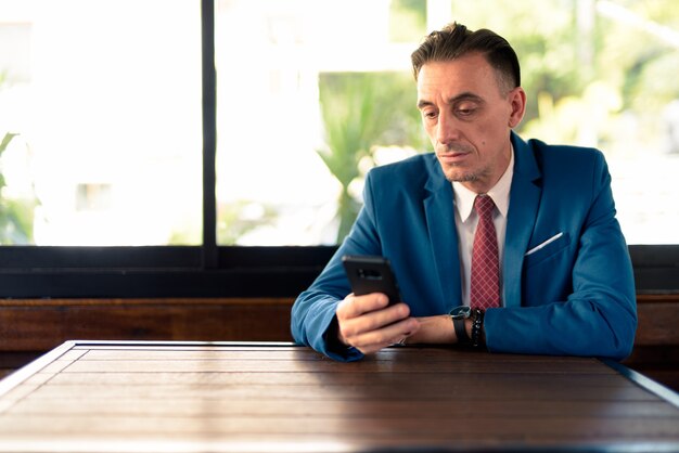 Portrait of mature handsome Italian businessman relaxing at the coffee shop