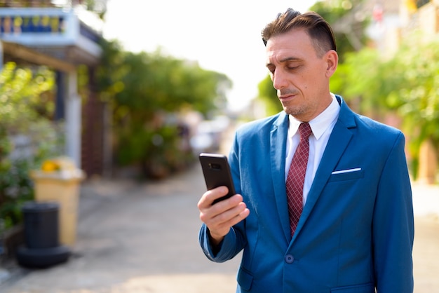 Portrait of mature handsome Italian businessman in the streets outdoors