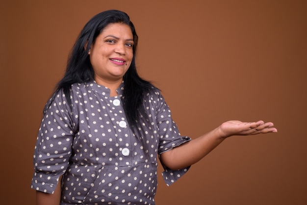 Portrait of mature Indian woman against brown background