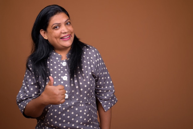 Portrait of mature Indian woman against brown background