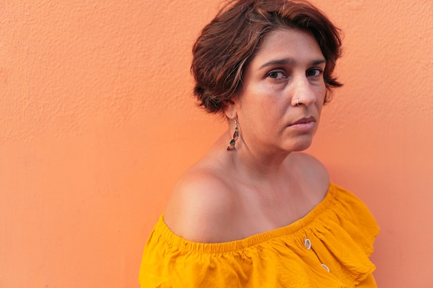 Portrait of mature Latin woman with colorful orange background.