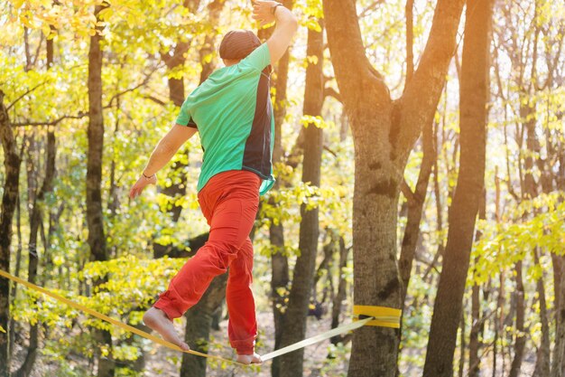 Portrait of a mature male highliner doing slackline balance training in the forest in autumn