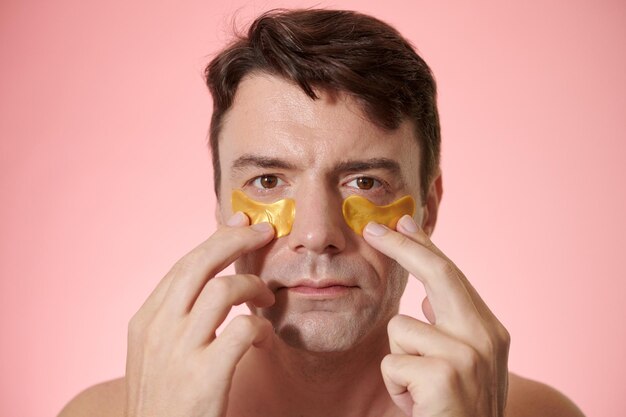 Photo portrait of mature man applying hydrogel patches to reduce fine lines