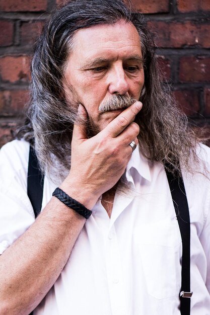 Photo portrait of mature man looking away against wall