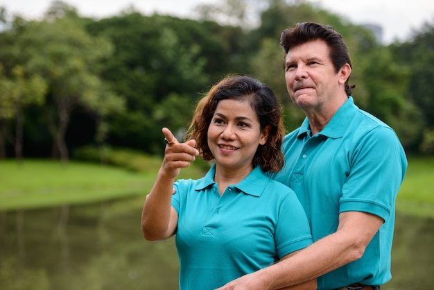 Ritratto di uomo maturo e donna asiatica matura come coppia sposata multietnica insieme e innamorata al parco all'aperto