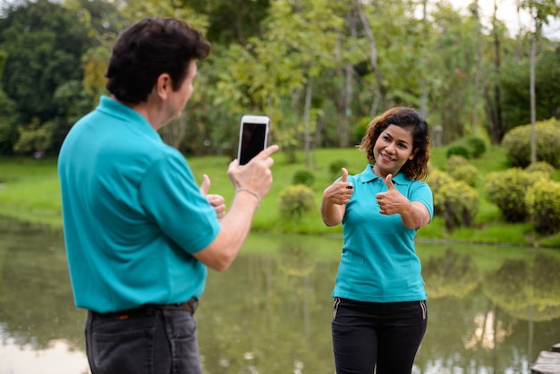 Portrait of mature man and mature Asian woman as multi ethnic married couple together and in love at the park outdoors