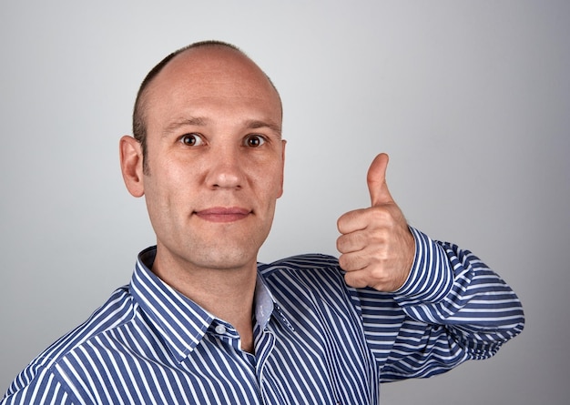 Photo portrait of mature man showing thumbs up against gray background