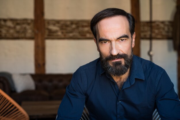 Portrait of a mature man sitting on the chair posing thoughtful