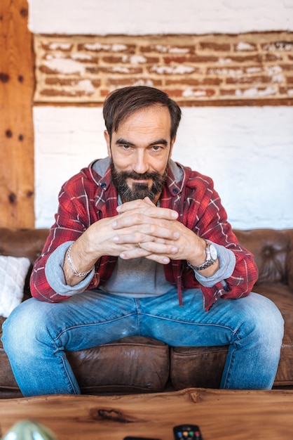 Portrait of a mature man sitting on the couch posing thoughtful