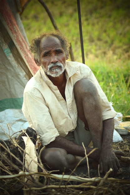 portrait of mature man sitting on field by tent