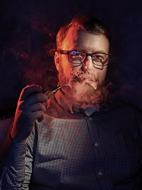 Photo portrait of mature man smoking while sitting against black background