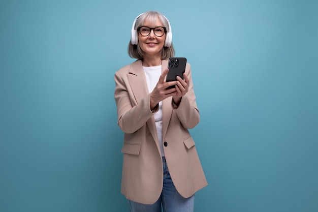 Portrait mature s business woman with wireless headphones on bright background with copy space