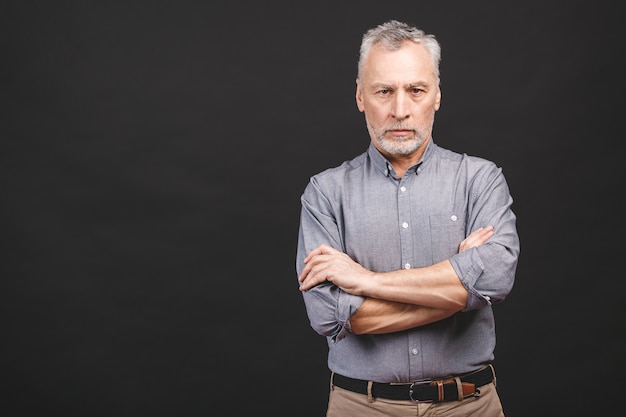 Portrait of a mature serious businessman wearing glasses isolated against black background