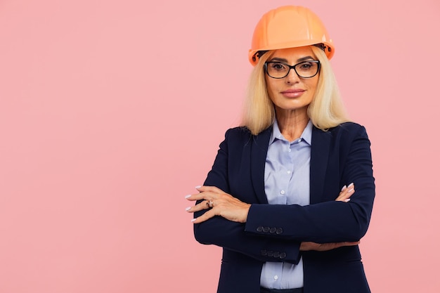 Ritratto di una donna matura architetto o ingegnere con gli occhiali su sfondo rosa