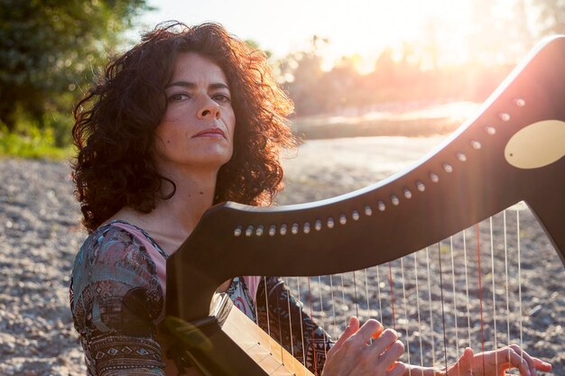 Photo portrait of mature woman playing harp outdoors