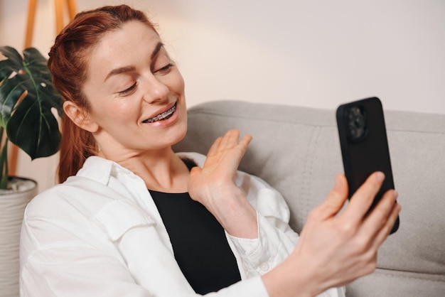 Portrait of mature woman showing braces on her teeth on video call