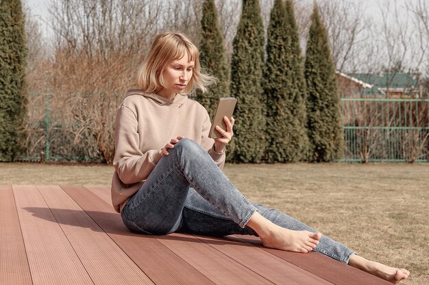 Portrait of mature woman sitting outdoors on terrace using smartphone