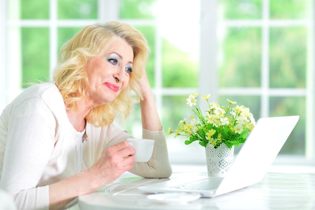 Foto ritratto di una donna matura seduta con un computer portatile moderno