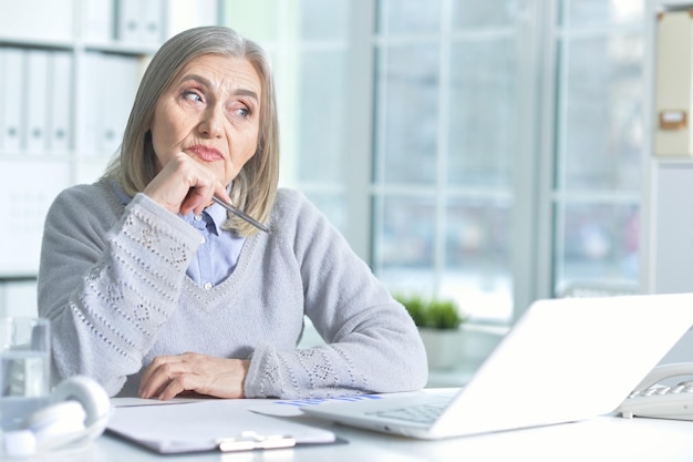 Photo portrait of mature woman using laptop at home