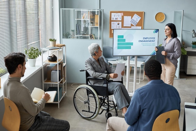 Portrait of mature woman using wheelchair while giving presentation in business meeting