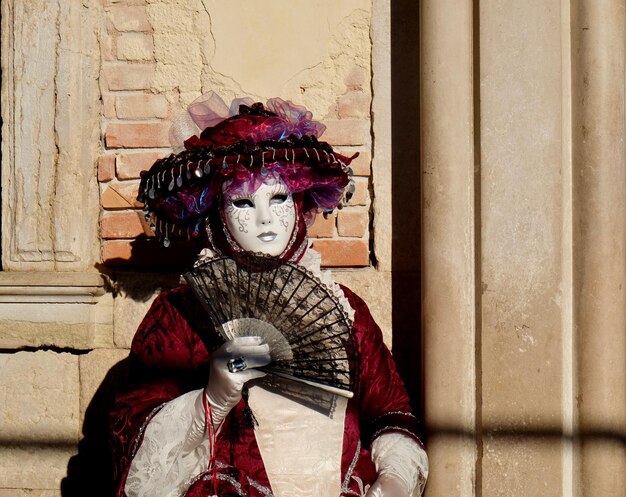 Foto ritratto di una donna matura che indossa un costume mentre tiene in mano un ventaglio durante il carnevale di venezia