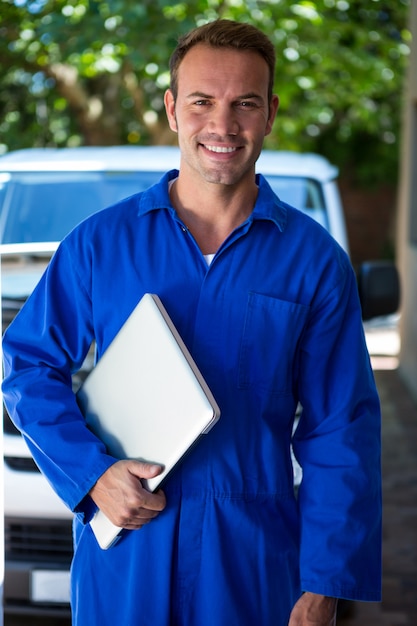 Portrait of mechanic holding a laptop