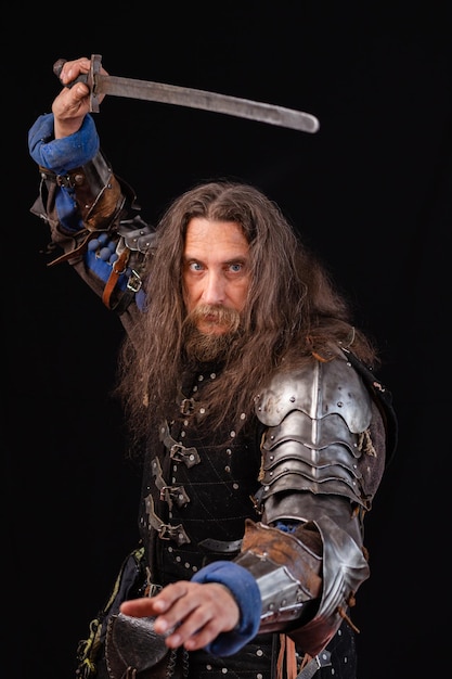 Photo portrait of a medieval knight with a characteristic historical appearance with a sword