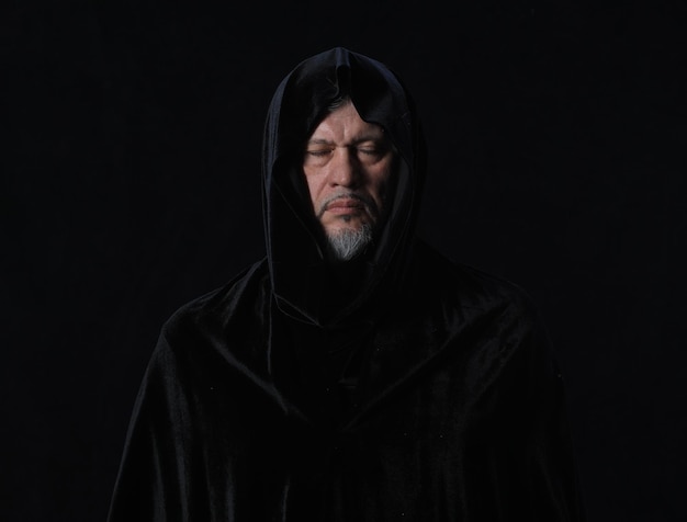 portrait of a medieval monk with a hood on a black background