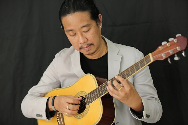 Portrait of men musician playing guitar in studio.