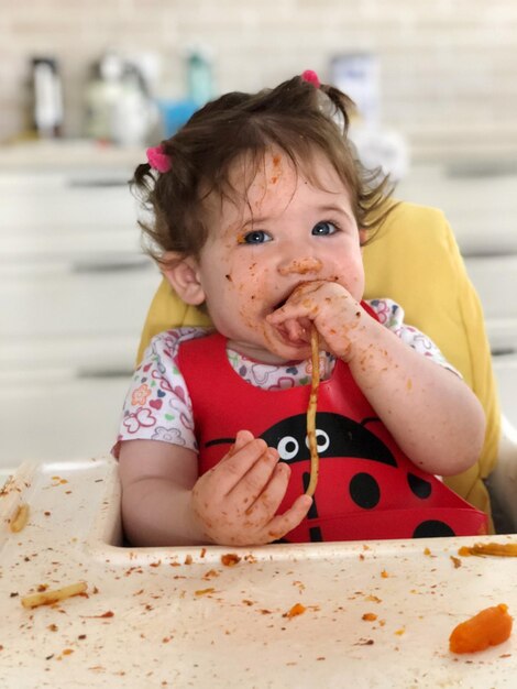 Portrait of messy girl sitting on high chair