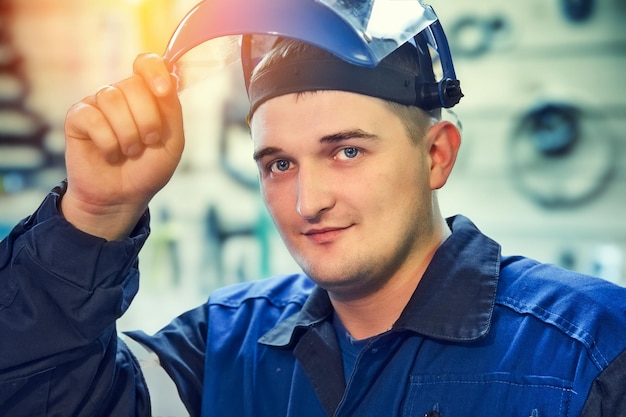 Portrait of Metal Locksmith Young Caucasian man looks into camera from under visor of protective mask Real worker