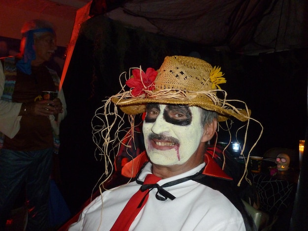 Photo portrait of mid adult man with painted face wearing halloween costume