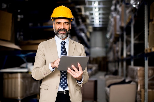 Portrait of middle-aged businessman with digital tablet in factory