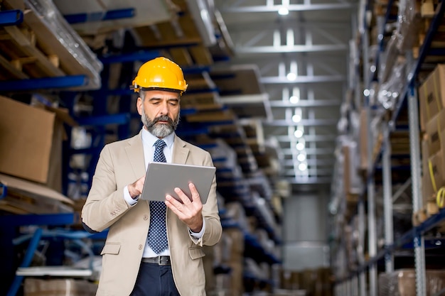 Portrait of middle-aged businessman with digital tablet in factory