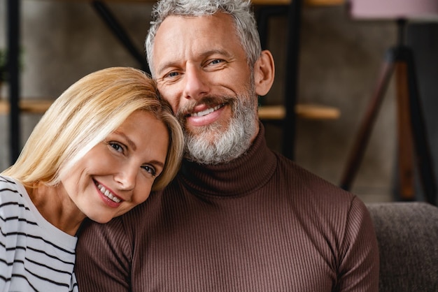 Portrait of middle aged couple bonding on couch at home living room