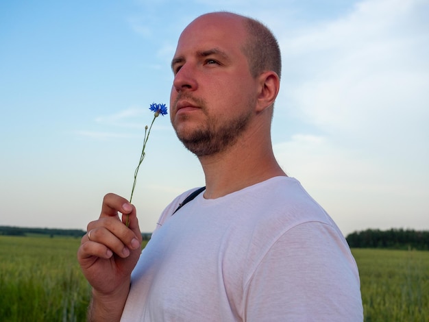 Portrait of a middle-aged man standing in a field with a flower in his hand and looking into the distance