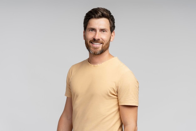 portrait of middle aged smiling bearded man looking at camera isolated on gray background